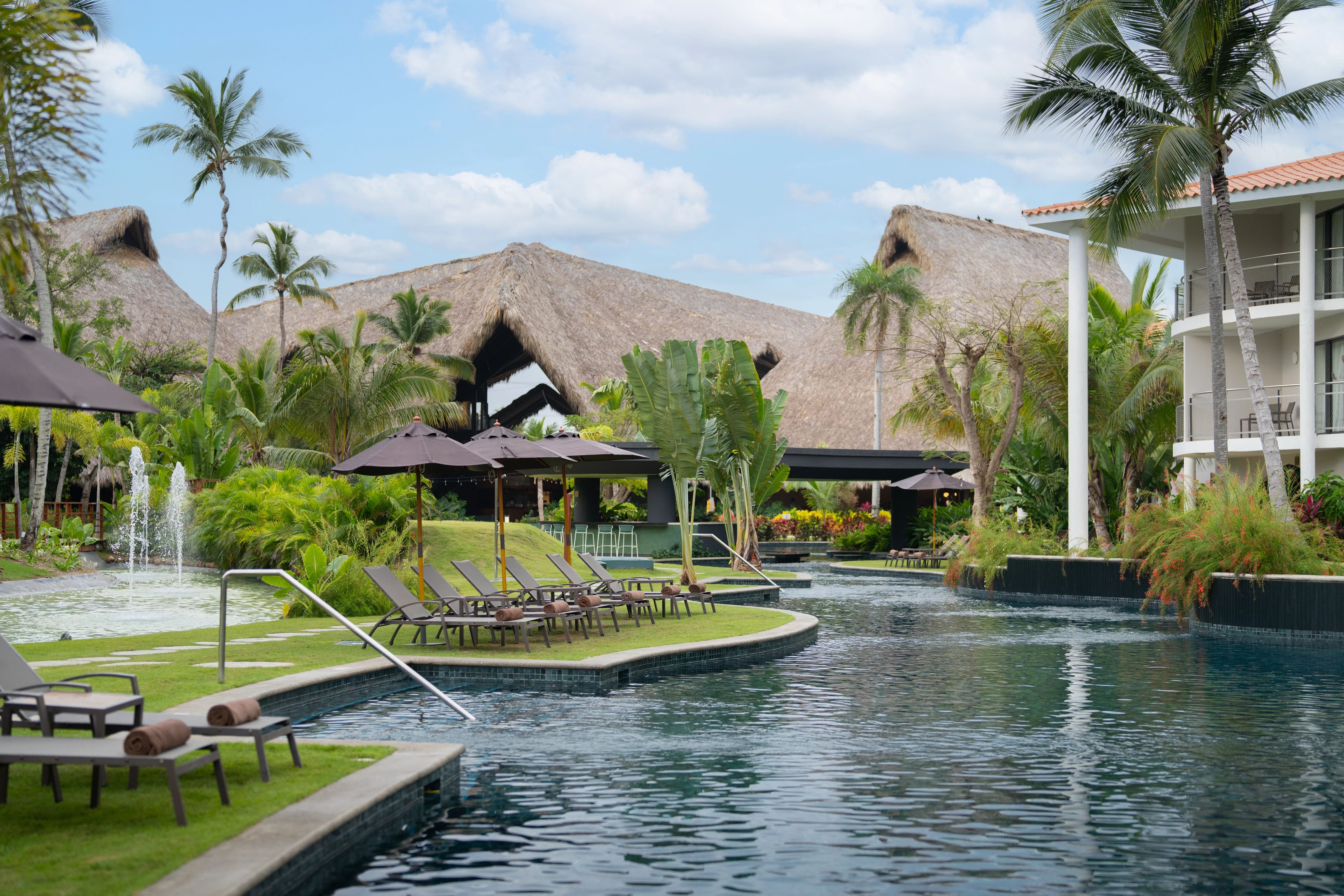 Piscina tipo río con áreas de descanso y palapas